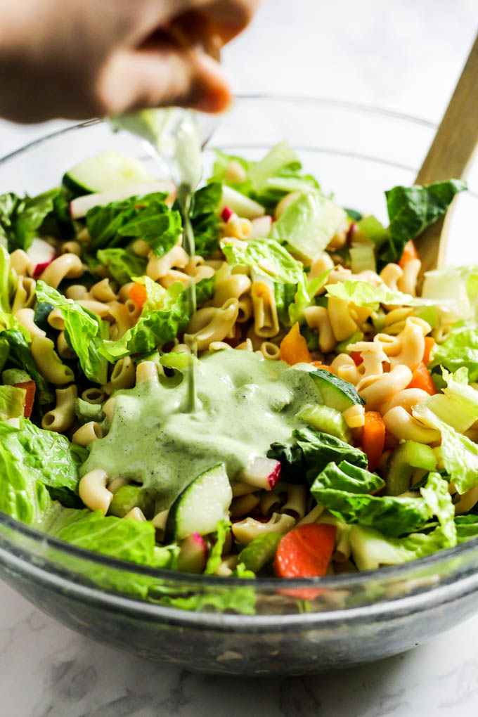 Vegan ranch dressing is poured onto a bowl of pasta salad