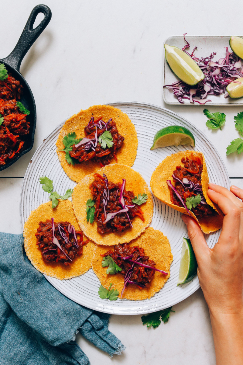 a plate of lentil tacos served with cilantro and lime wedges