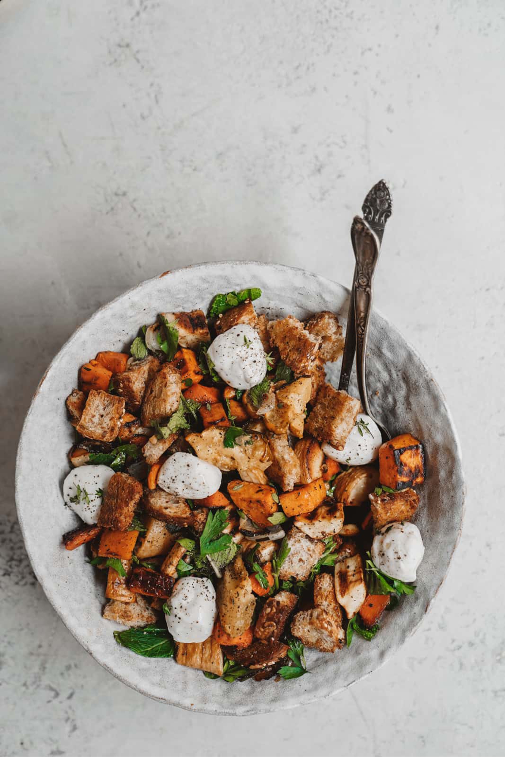 a vegan panzanella salad featuring squash, croutons, herbs and vegan mozzarella 